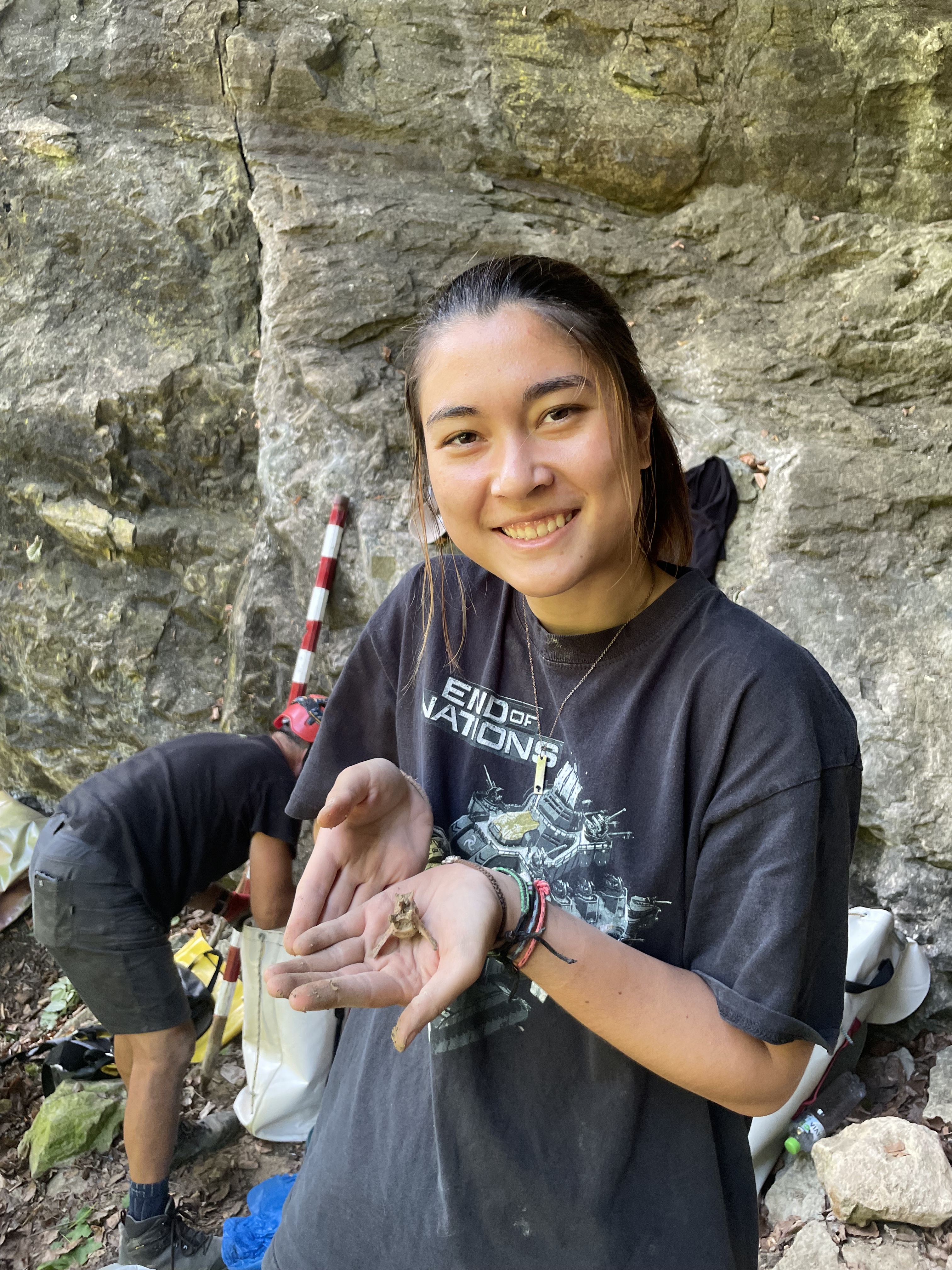 Jasmine on the excavation site holds a bone smiling at the camera. 