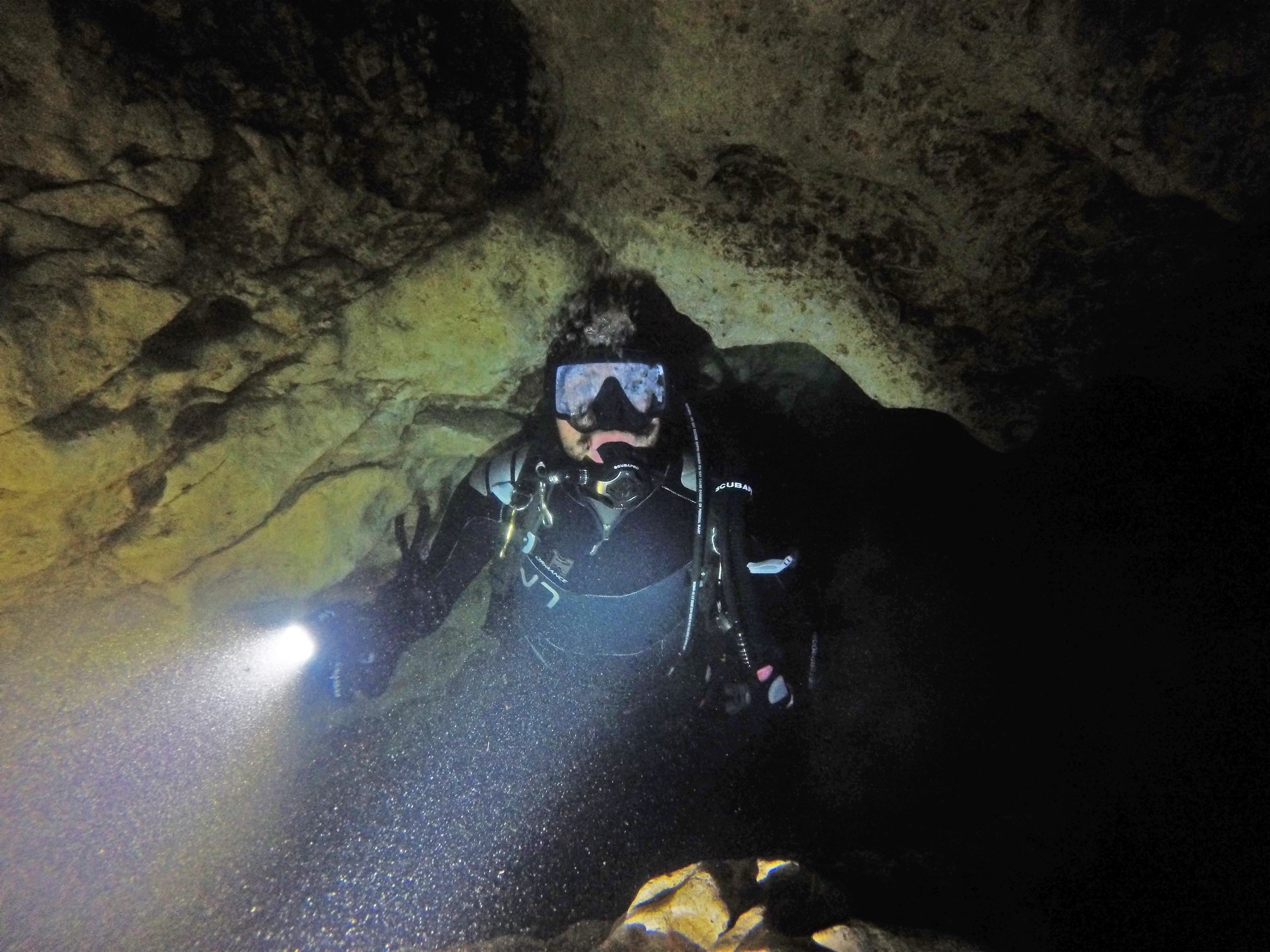 Person in full scuba gear underwater in a dark cave. 