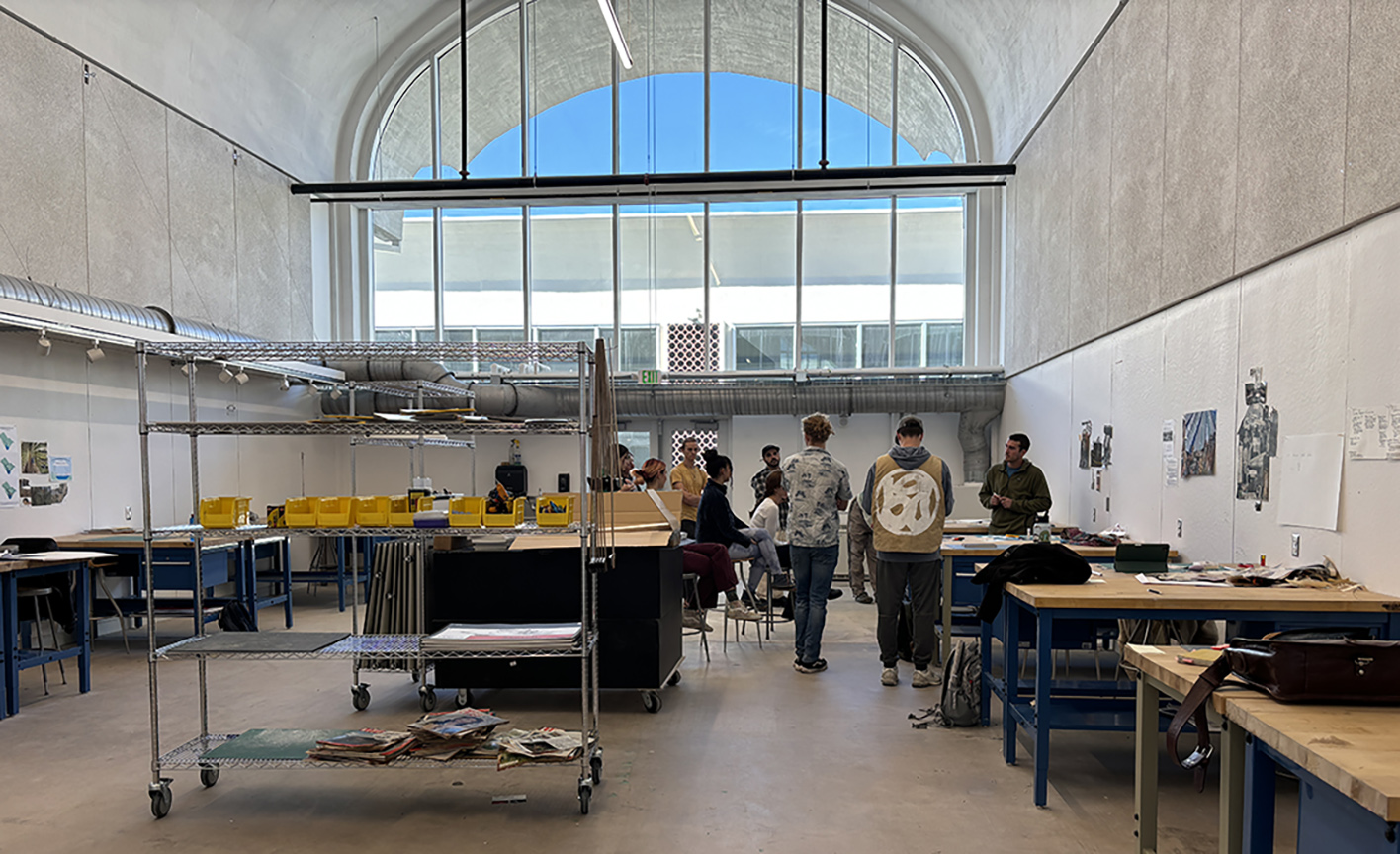 a group of students crowed around a table at one end of a classroom