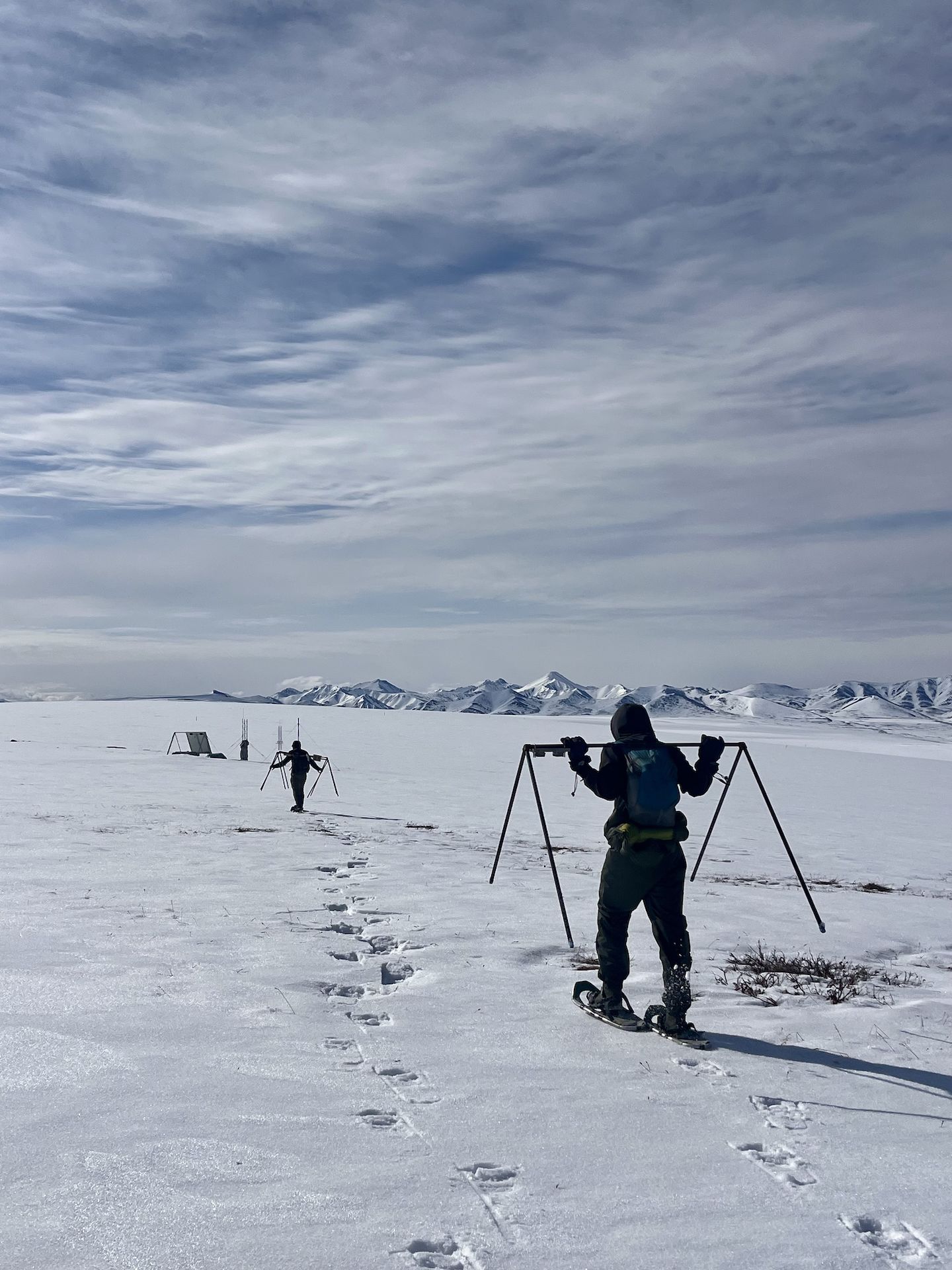 Students carrying equipment through snow while conducting research in the Alaskan Arctic