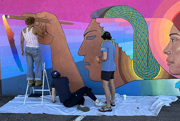 CC Art students (from l-r) Vivienne Diggs, Will Gerash (seated), and Gavin Cardamone paint parts of Arte Mestiza for their final Block 1 project.  Photo by Jean Gumpper / Colorado College