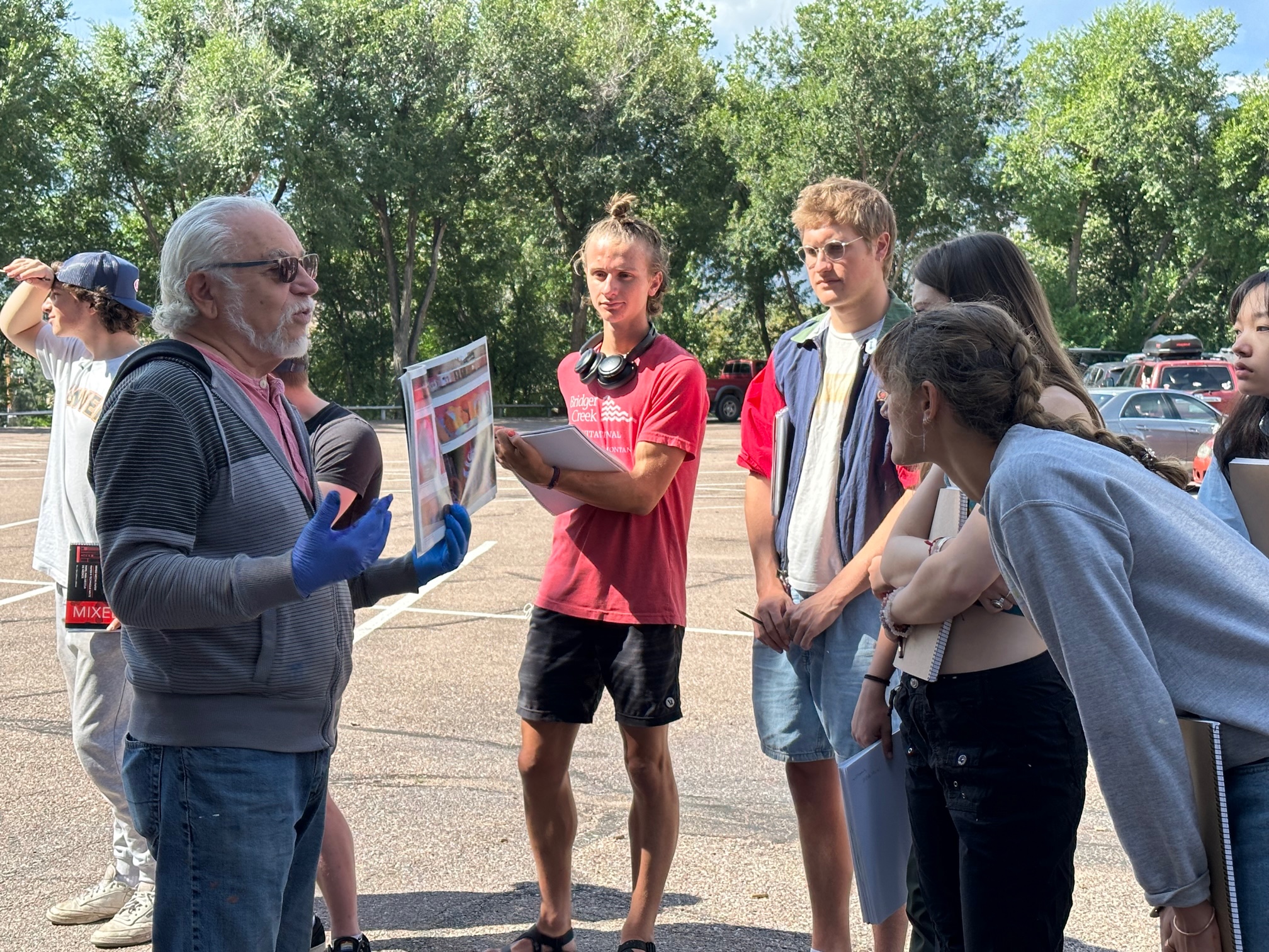 Martinez shares a book of his work with students from a CC Arts class, who are learning about mural paintings. Photo by Alexa Gromko / Colorado College