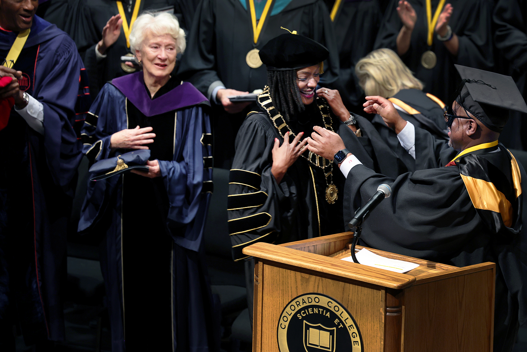 Former CC President Kathryn Mohrman and former Co-Interim President Mike Edmonds look on as current President Manya Whitaker is bestowed with the "Chain of Office," a traditional symbol of the president's authority and the responsibility of their office by Board of Trustees Chair Kyle Samuel '92. Photo by Jamie Cotten / Colorado College