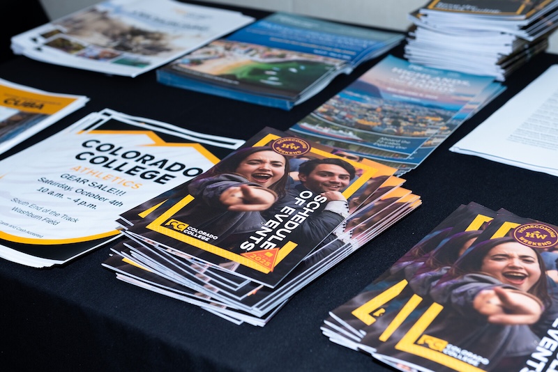 A schedule of events brochure stacked with other collateral on a table